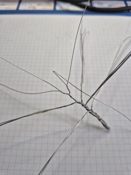 Draadstructuur met verschillende vertakkingen op een geruite ondergrond.