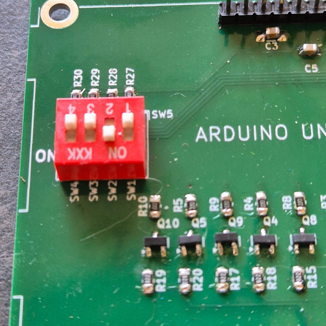 DIP-Switch Groene printplaat met Arduino-onderdelen en een rode schakelaar met drie posities.