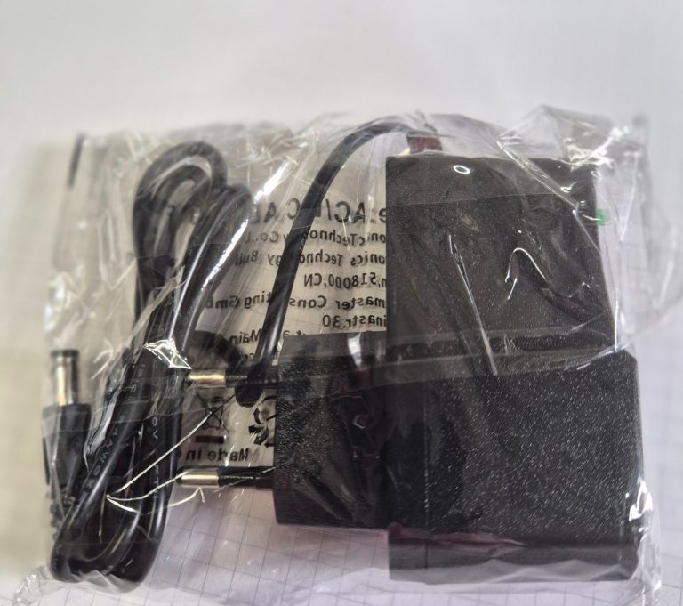 Zwart oplader met kabel in plastic verpakking.