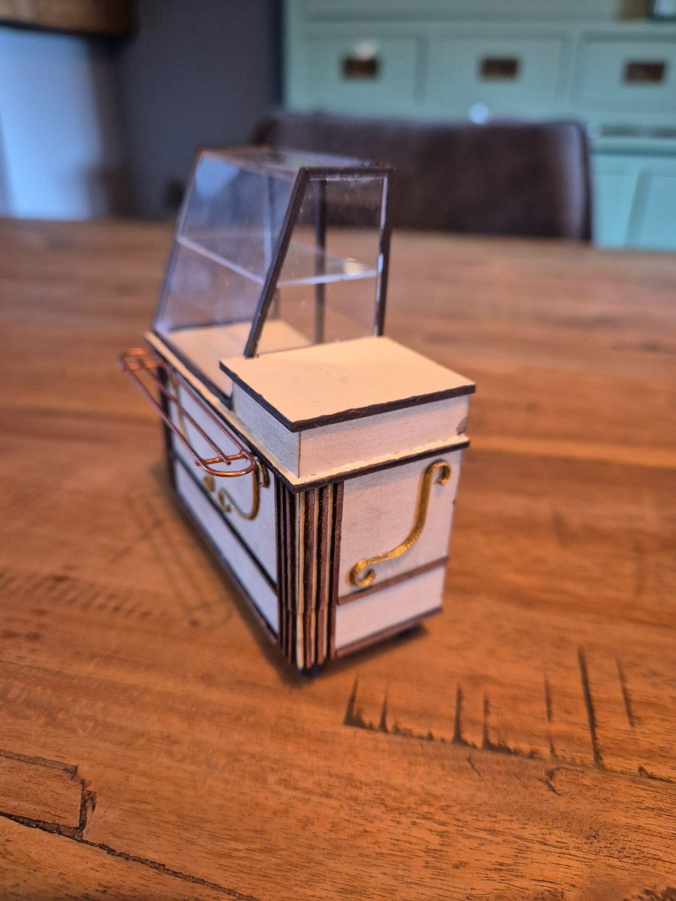 Miniatuur reclamekar met doorzichtige afscherming op een houten tafel.